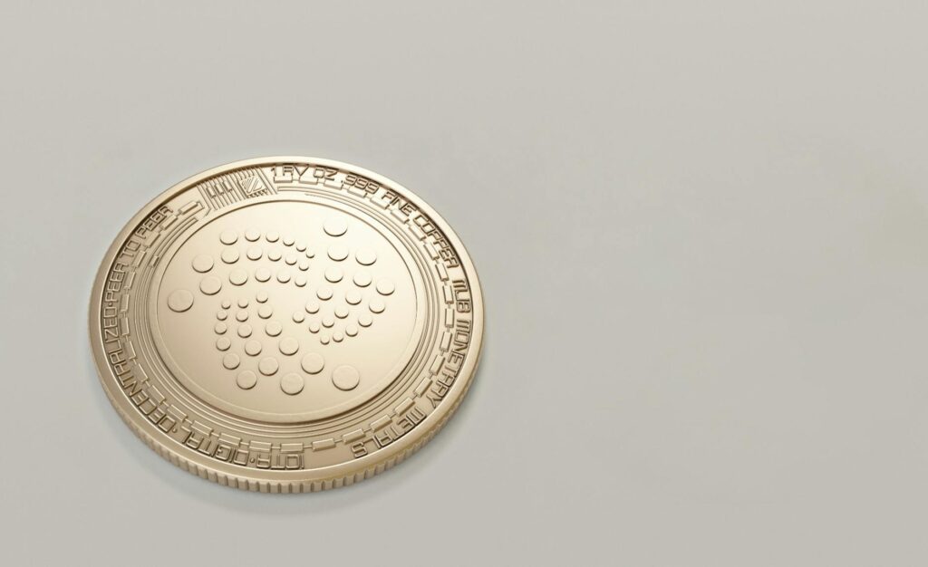 High-quality image of a gold IOTA cryptocurrency coin on a plain background, ideal for finance concepts.
