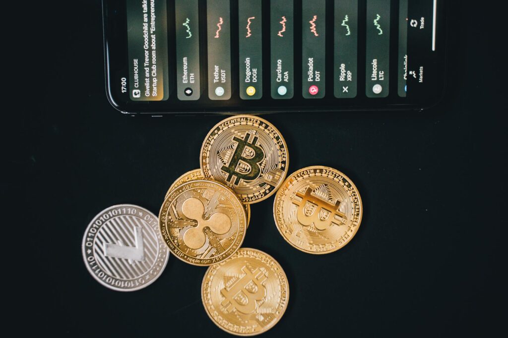 Close-up of various cryptocurrencies and a smartphone showing market trends.