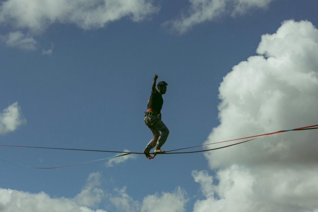 A man balances on a slackline high above with a dramatic sky as the backdrop.