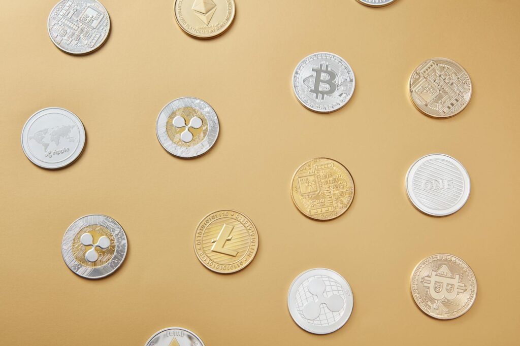 A flat lay of various cryptocurrency coins on a gold background, showcasing digital currency diversity.