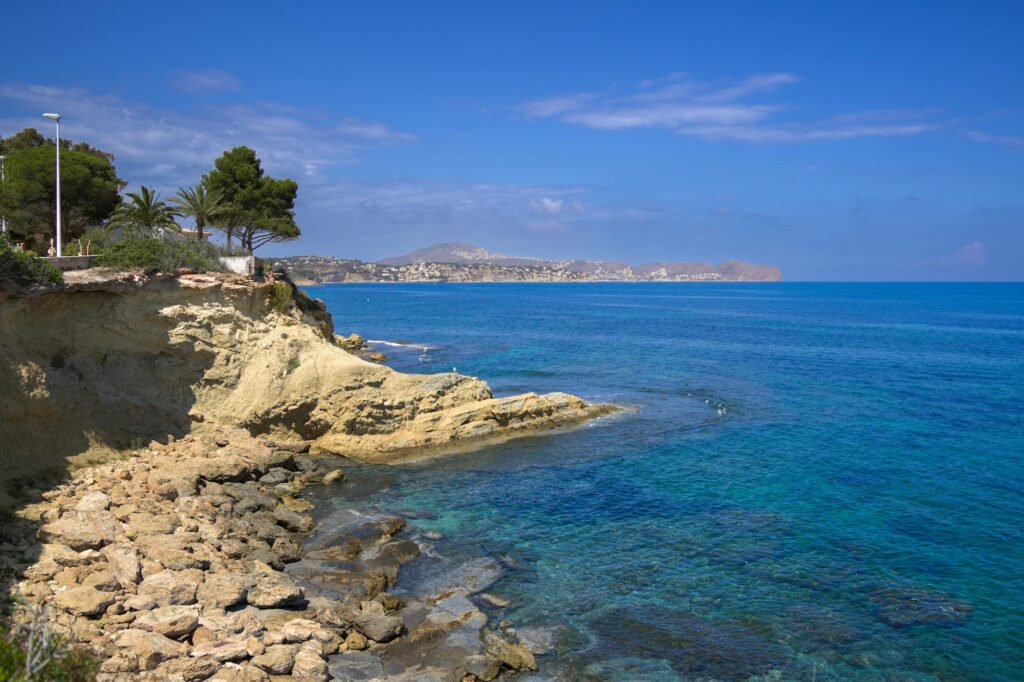 Beautiful coastal scene in Calpe, Spain with clear blue waters and rocky cliffs.